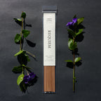 Requiem Incense Company Amber & Moss incense sticks with green leaves and purple flowers on a dark background