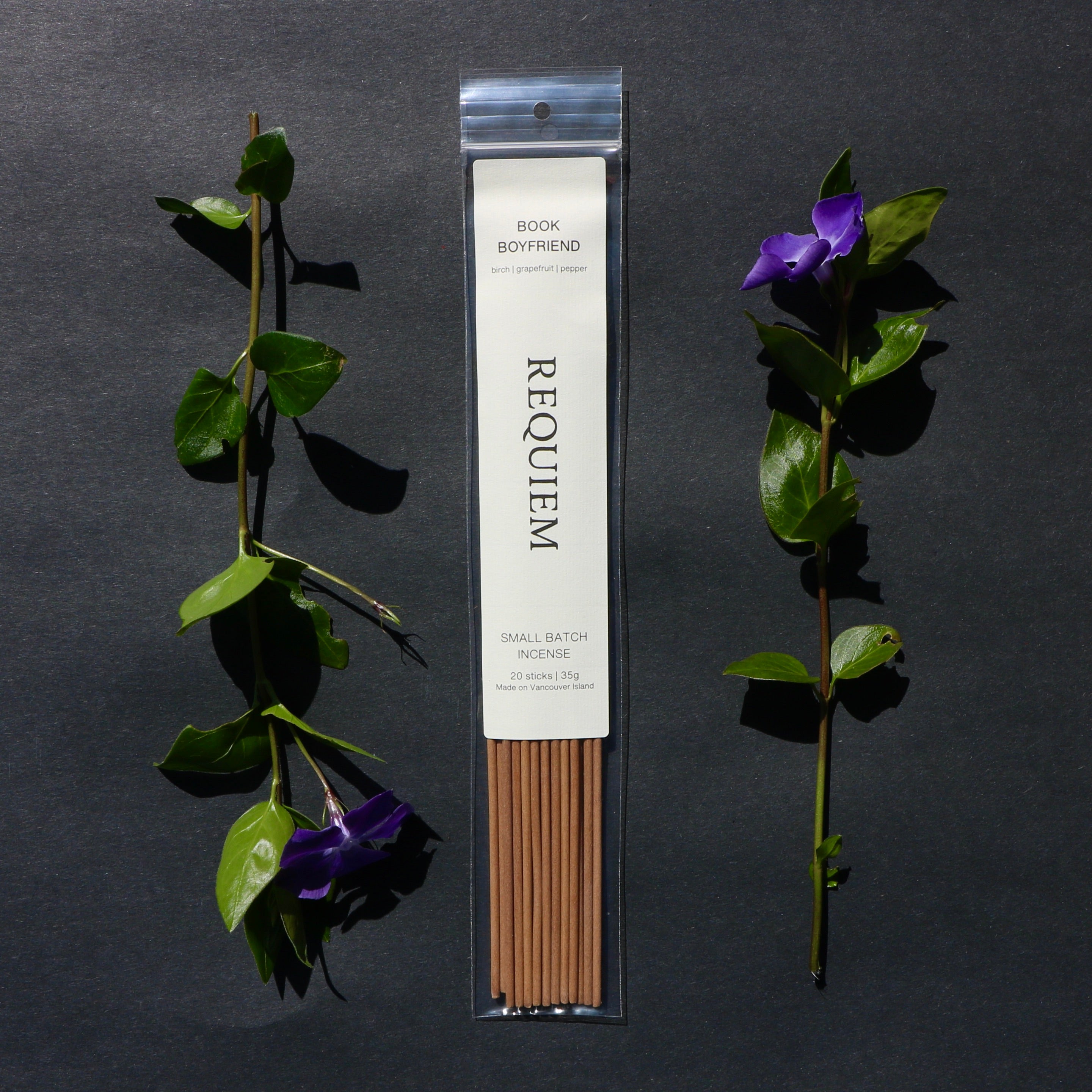 Requiem Incense Company Book Boyfriend incense sticks with green leaves and purple flowers on a dark background