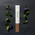 Requiem Incense Company Cedar & Rain incense sticks with green leaves and purple flowers on a dark background