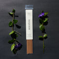 Requiem Incense Company Sage & Vanilla incense sticks with green leaves and purple flowers on a dark background