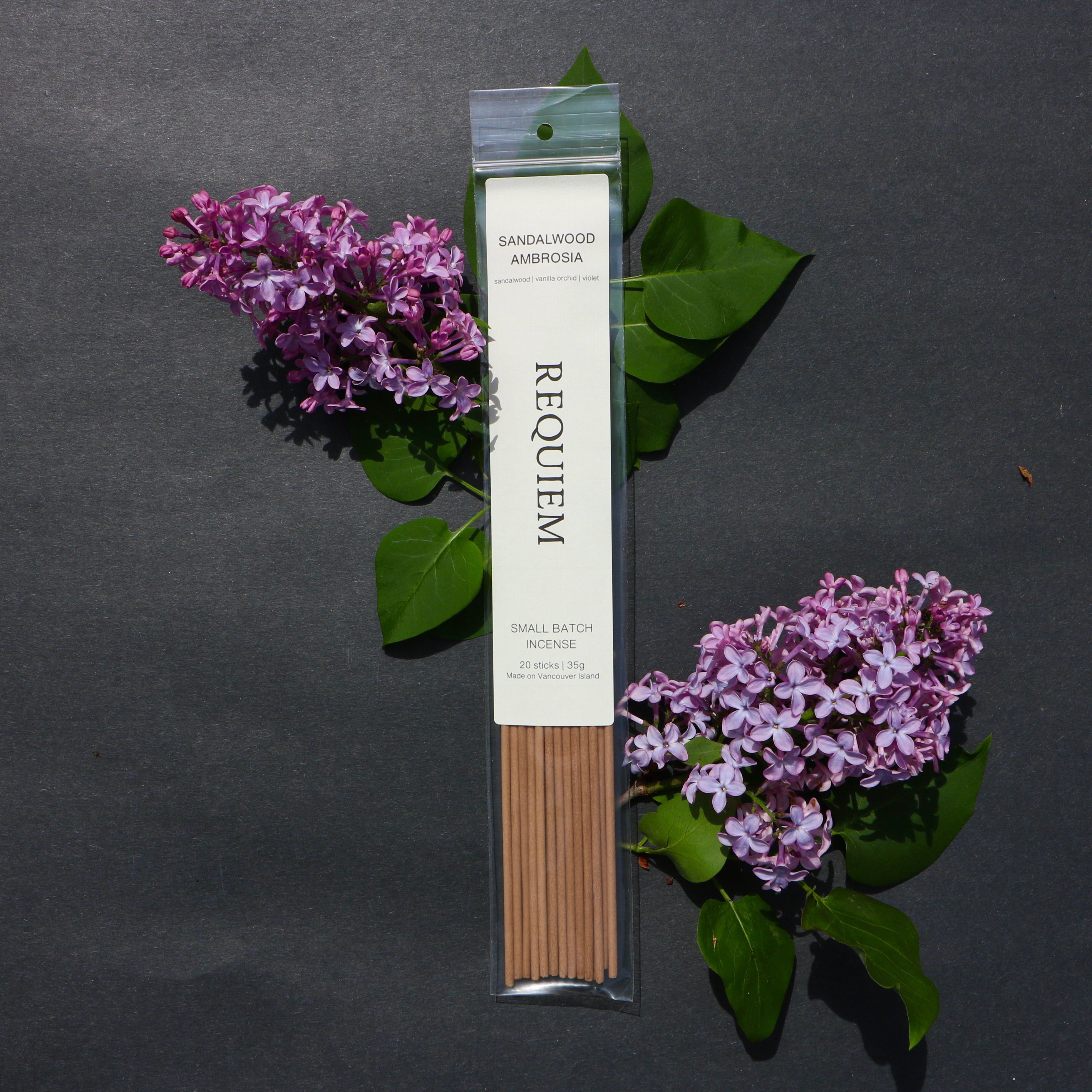 Requiem_Incense_Company_Small_Batch_Incense_Sticks_Sandalwood_Ambrosia_Made_in_Canada - Packaged incense sticks labeled 'Requiem' with purple flowers and green leaves on a dark background