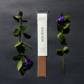 Requiem Incense Company Vancouver Island Fog incense sticks with green leaves and purple flowers on a dark background