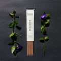 Requiem Incense Company West Coast Rainforest incense sticks with green leaves and purple flowers on a dark background