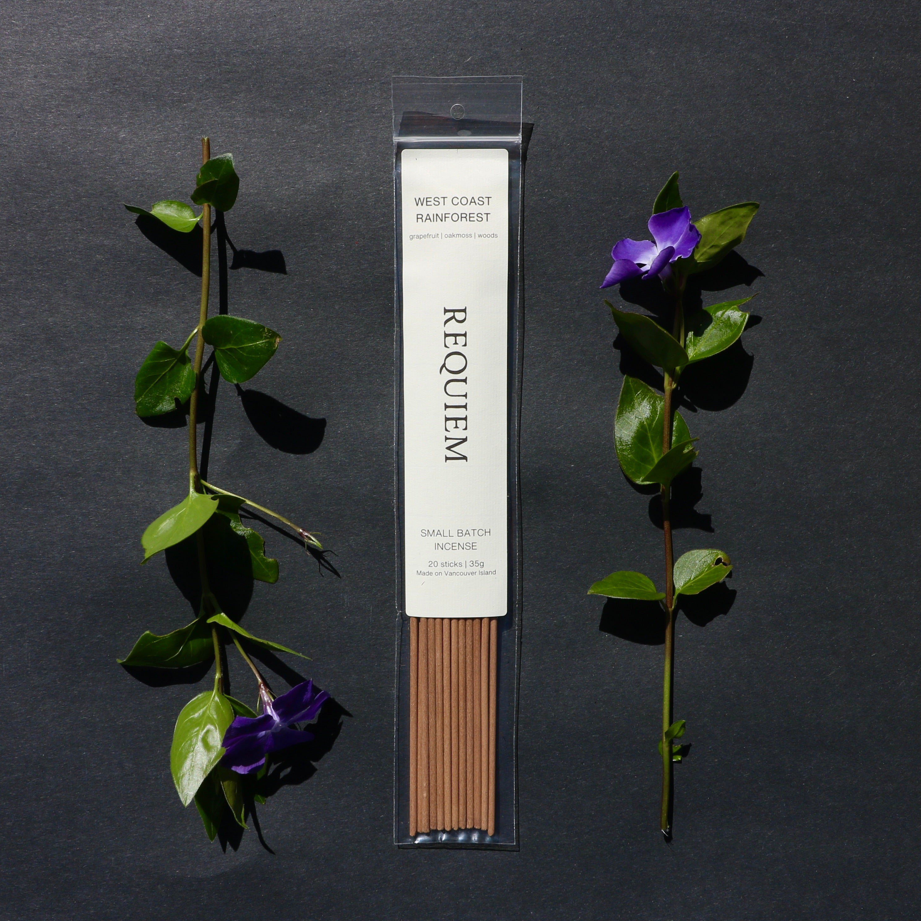 Requiem Incense Company West Coast Rainforest incense sticks with green leaves and purple flowers on a dark background