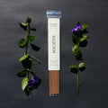Requiem Incense Company Wild Rose & Ginger incense sticks with green leaves and purple flowers on a dark background