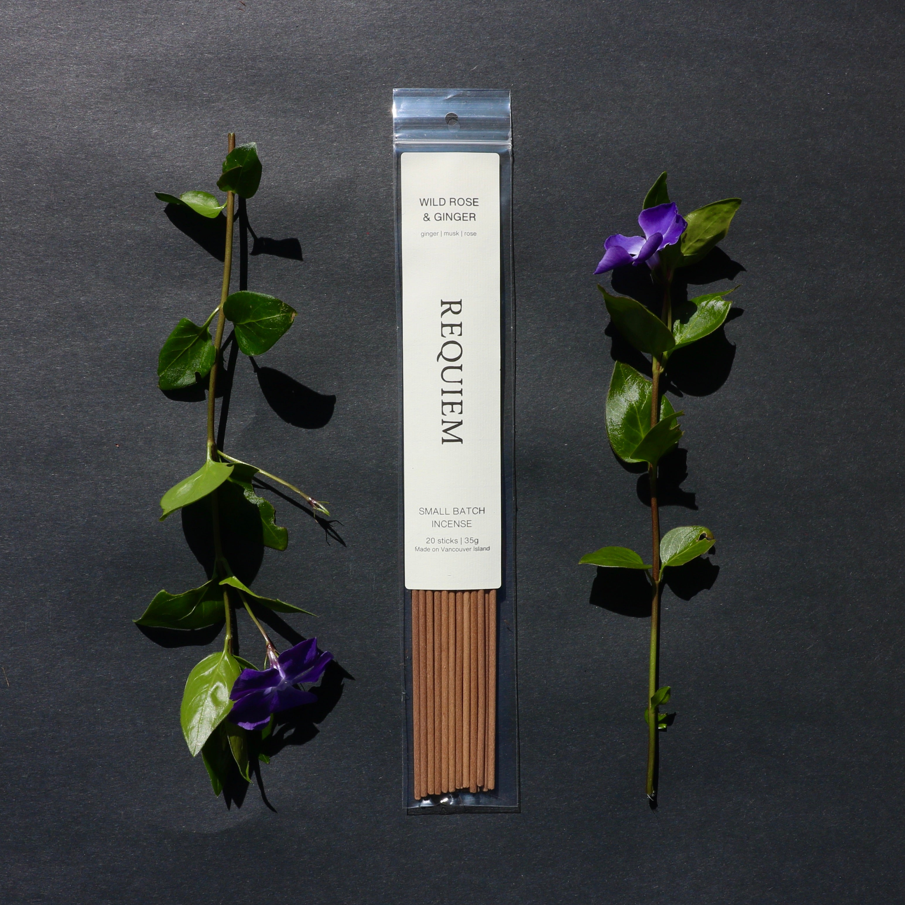 Requiem Incense Company Wild Rose & Ginger incense sticks with green leaves and purple flowers on a dark background